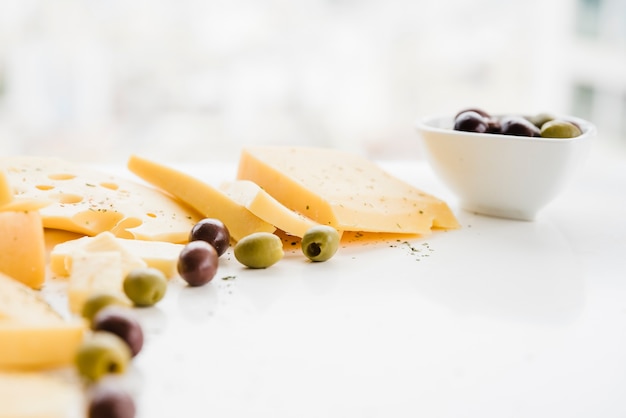 Green olives with cheese slices over the white desk