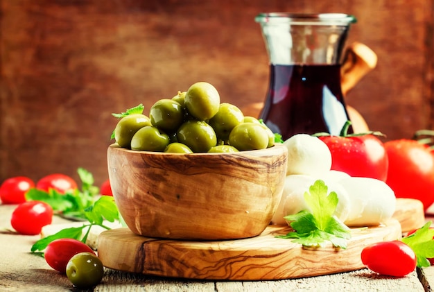 Green olives in a wooden bowl selective focus