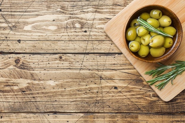 Green olives in wooden bowls on wooden table 