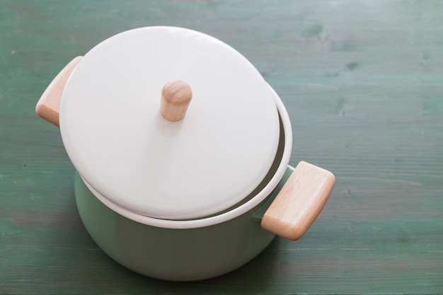 Green open cooking pan on green wooden