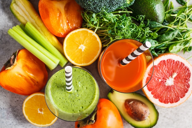 Frullato di disintossicazione verde e arancione in vetro. ingredienti per lo sfondo di frullato di disintossicazione. concetto di cibo sano.