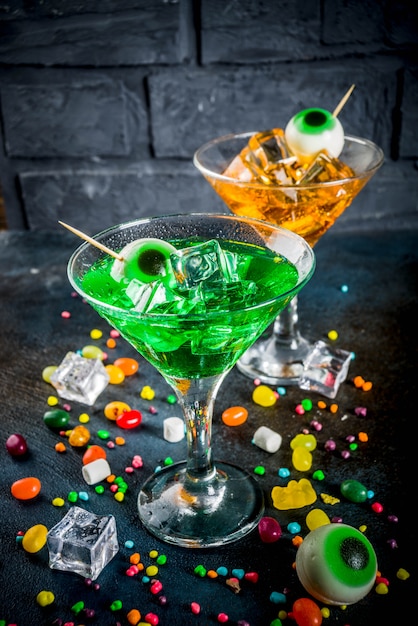 green, orange martini cocktail with ice cubes and a decor of marshmallow eyes