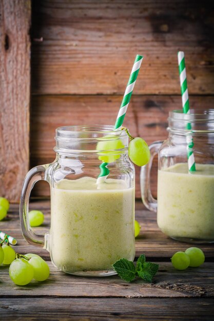 Green organic detox grape smoothie in glass mason jar on wooden rustic background