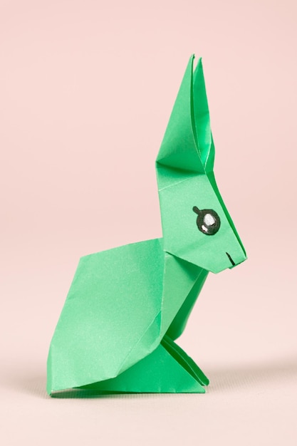 Foto un coniglio origami verde su sfondo beige