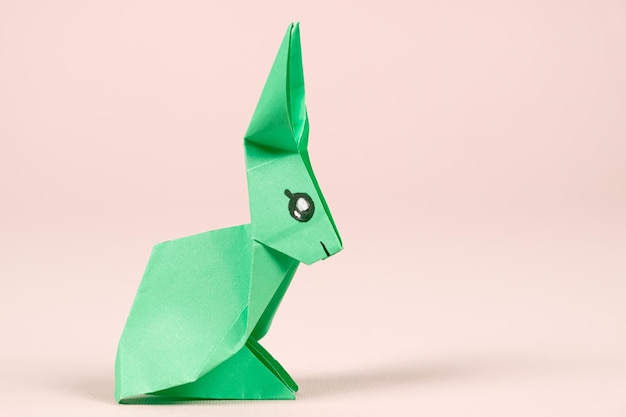 A green origami rabbit on a beige background