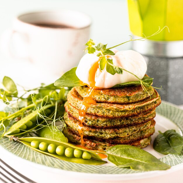 Pancake verdi con spinaci e uovo in camicia. gustosa colazione europea sana.
