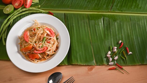 Green papaya salad and ingredients on banana leaf Thai food concept Top view