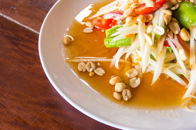 Green Papaya Salad or Som Tum Thai on wooden table