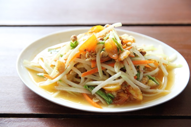 Green papaya salad on wood background