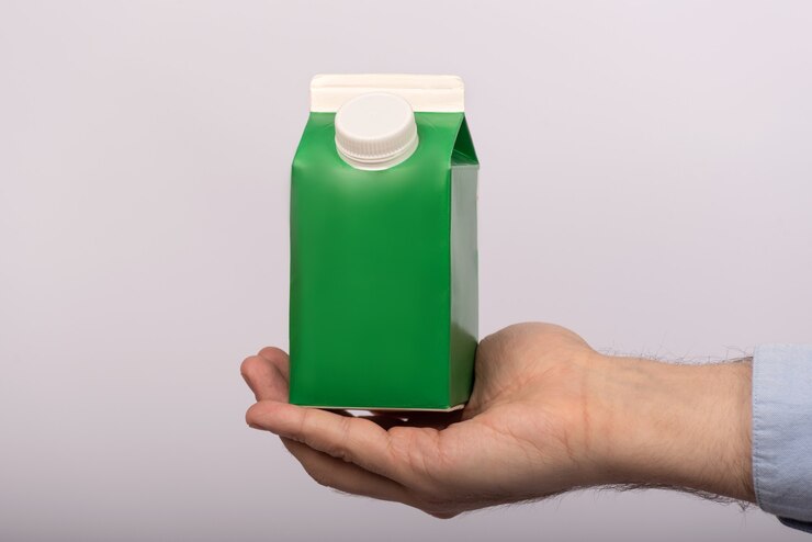 Green paper bag in mans hand on white . Juice yogurt milk packaging. mock up.