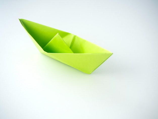 Green paper boat laid on white background.