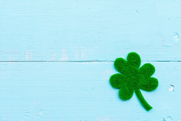 Photo green paper clover leaf on pastel white and blue wooden table background texture.