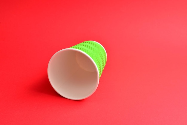 Green paper cup on a red background Copy space