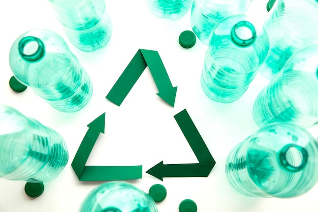 Green paper recycling symbol with empty plastic water bottles