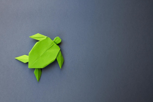 Зеленая бумажная черепаха оригами изолирована на сером фоне