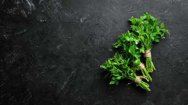 Green parsley on a black stone background Top view Free space for your text