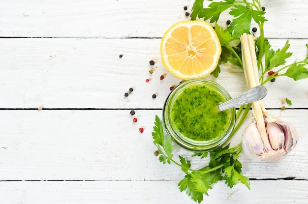 Green parsley sauce Ingredients for chimichurri sauce On a white wooden background Top view free space for your text