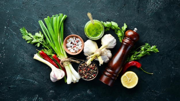 Green parsley sauce olive oil and spices Ingredients for chimichurri sauce On a black background Top view free space for your text