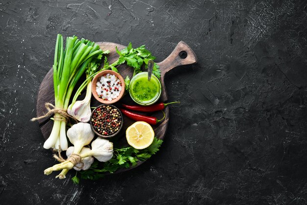 Photo green parsley sauce olive oil and spices ingredients for chimichurri sauce on a black background top view free space for your text