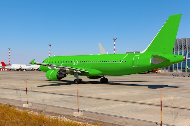 Green passenger airplane at the airport on sunny day