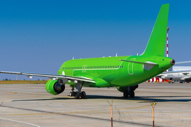 Green passenger airplane at the airport on sunny day