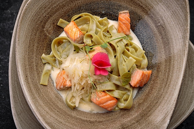 Green pasta with salmon and cheese on a dark