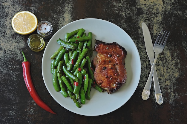 Green pea pods and pork steak on a plate. Keto diet. 