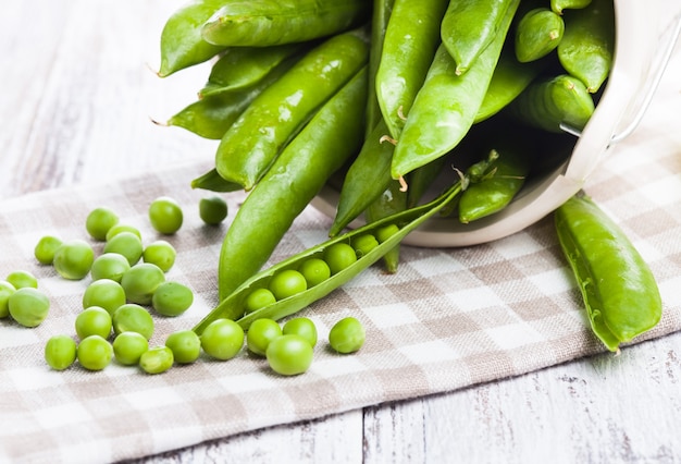 Green pea scattered on the napkin and unpeeled pea