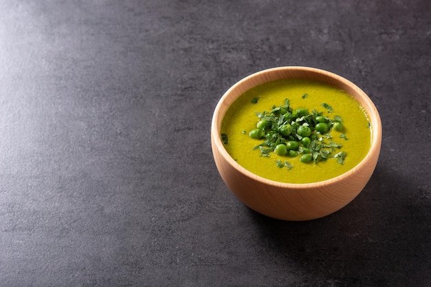 Green pea soup in a bowl on black slate background