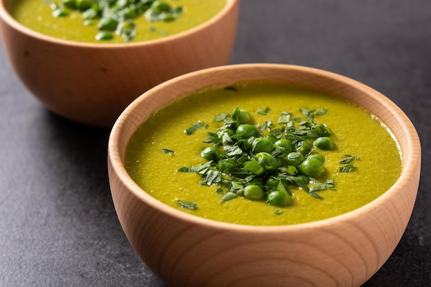 Green pea soup in a bowl on black slate background