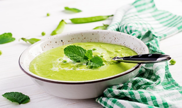 Green pea soup in bowl on wooden table, French cuisine.