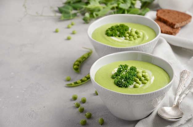 Green pea soup on gray concrete or stone background.