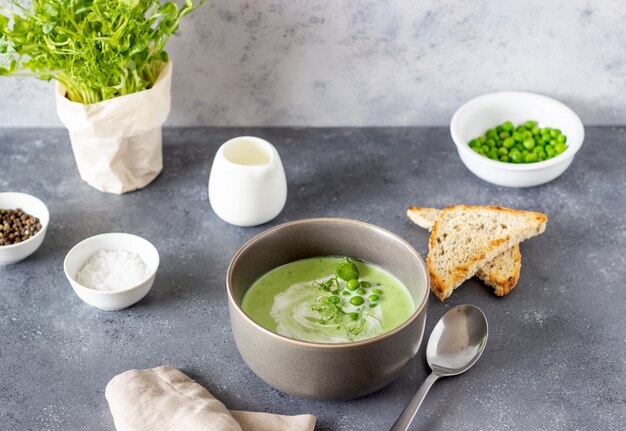 Green pea soup on a gray table. Healthy eating. Vegetarian food. Recipe. Diet.