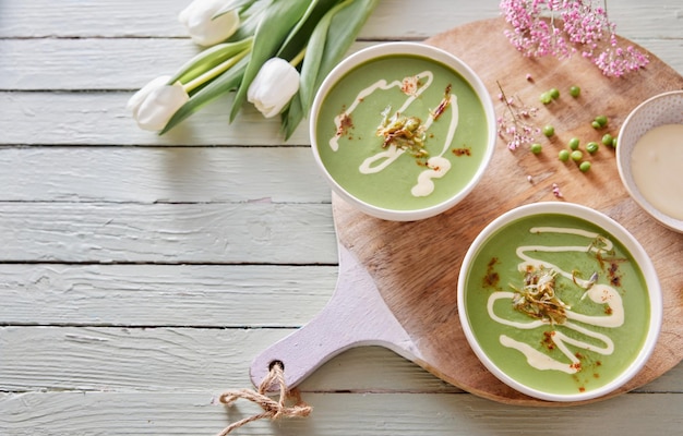 Green pea soup served on wooden table