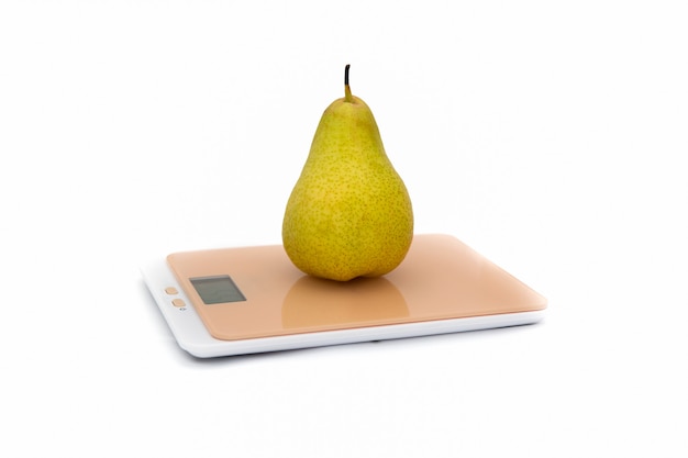 Green Pear on kitchen scale on white.