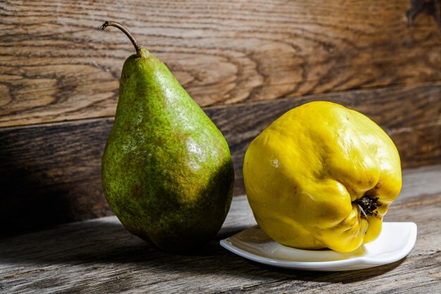 Green pear and a yellow quince are on the wooden kitchen table Village