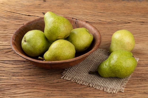 Green pears in a bowl over wooden table.