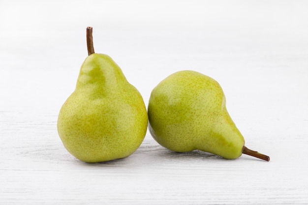 Green pears on white wooden background