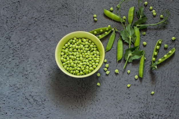 Green peas in bowl and on branches in pods