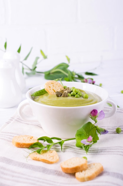 Foto zuppa di crema di piselli con crostini di pane in una ciotola bianca