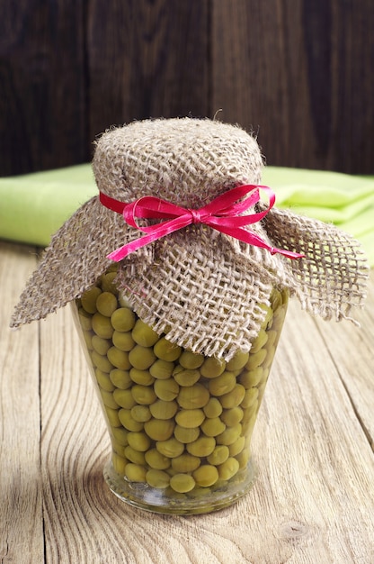 Green peas in glass jar on wooden table