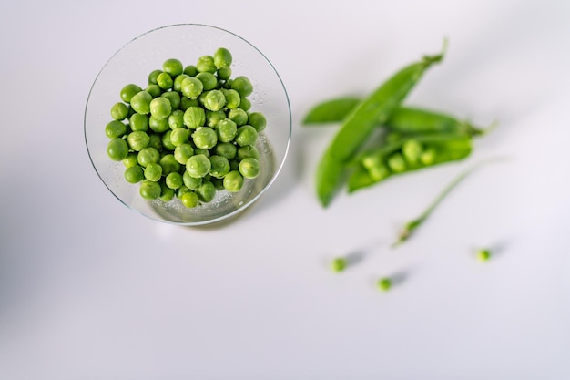 Green peas in a glass on white wooden background Concept of healthy eating fresh vegetables Copy space Top view