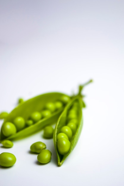 흰색 배경에 포드에 있는 녹색 완두콩 건강한 채식 음식