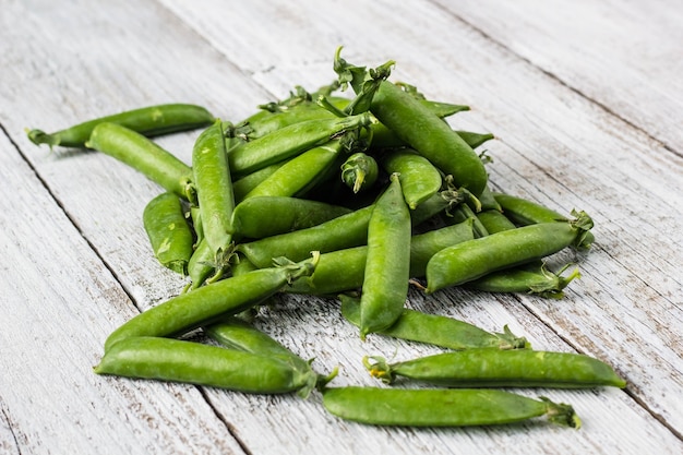 Green peas pods on a white wooden table top view