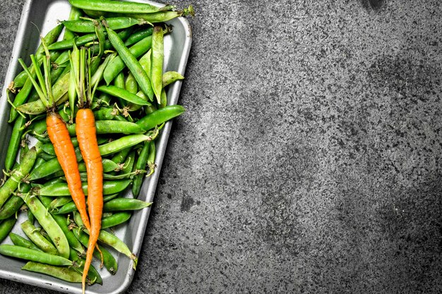 Green peas with carrots on a steel tray.