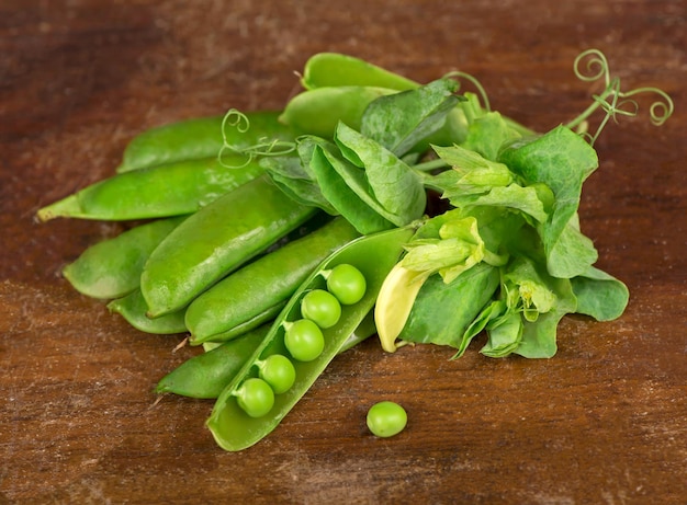 Photo green peas with leaves on wooden background