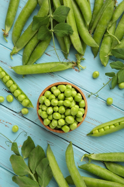 Green peas in wooden bowl on blue wooden background. vertical\
photo