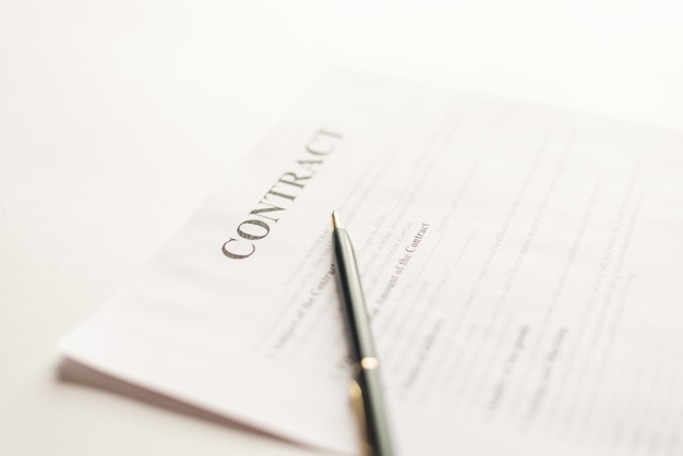 Green pen and contract papers on white desk