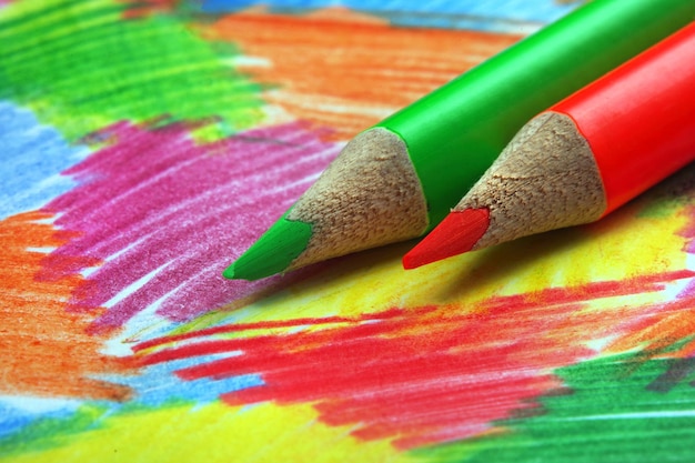 Green pencils with red and yellow markers on a colorful table cloth.