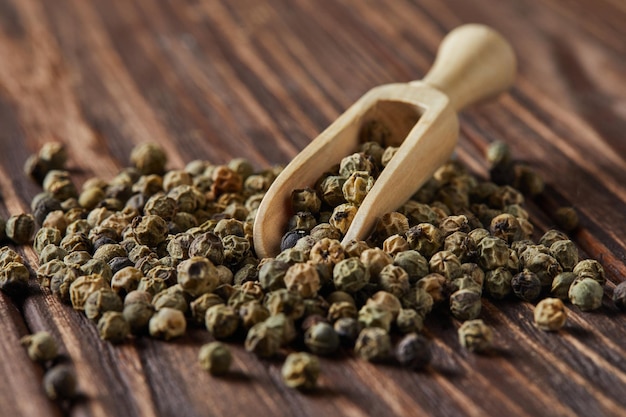 Green peppercorns with wooden spatula scattered on wooden vintage background